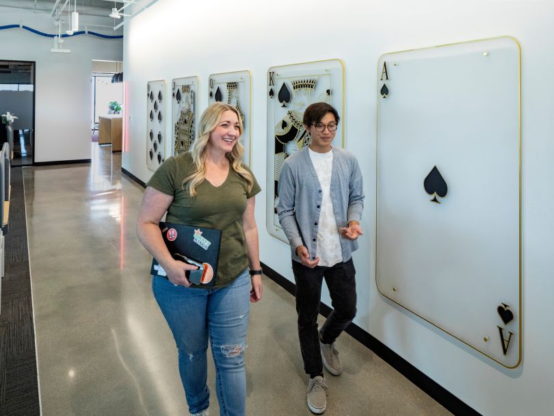 Two DraftKings team members chat while walking through a hallway in the company’s office